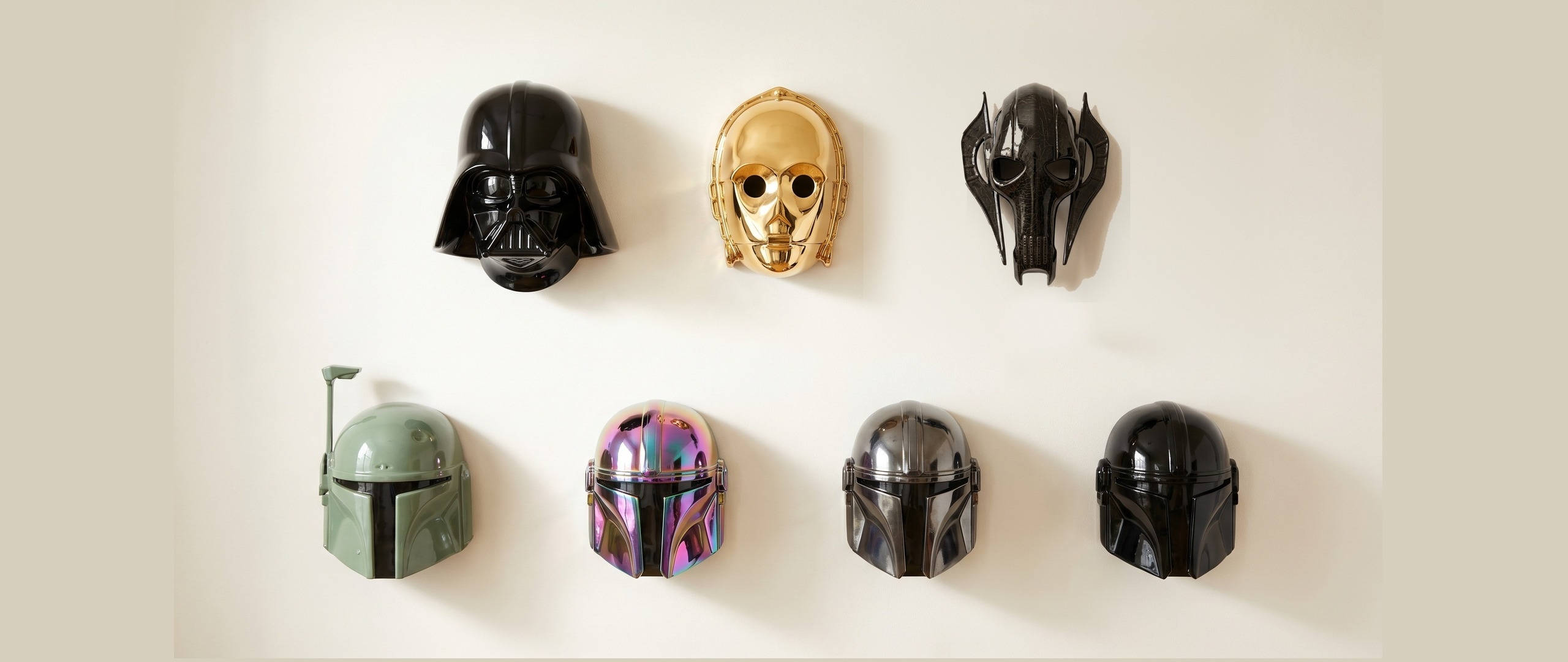 Five ceramic wall masks — Vader, Gold Protocol, Grievous, Boba Fett and the Armorer — arranged on a warm cream plaster wall